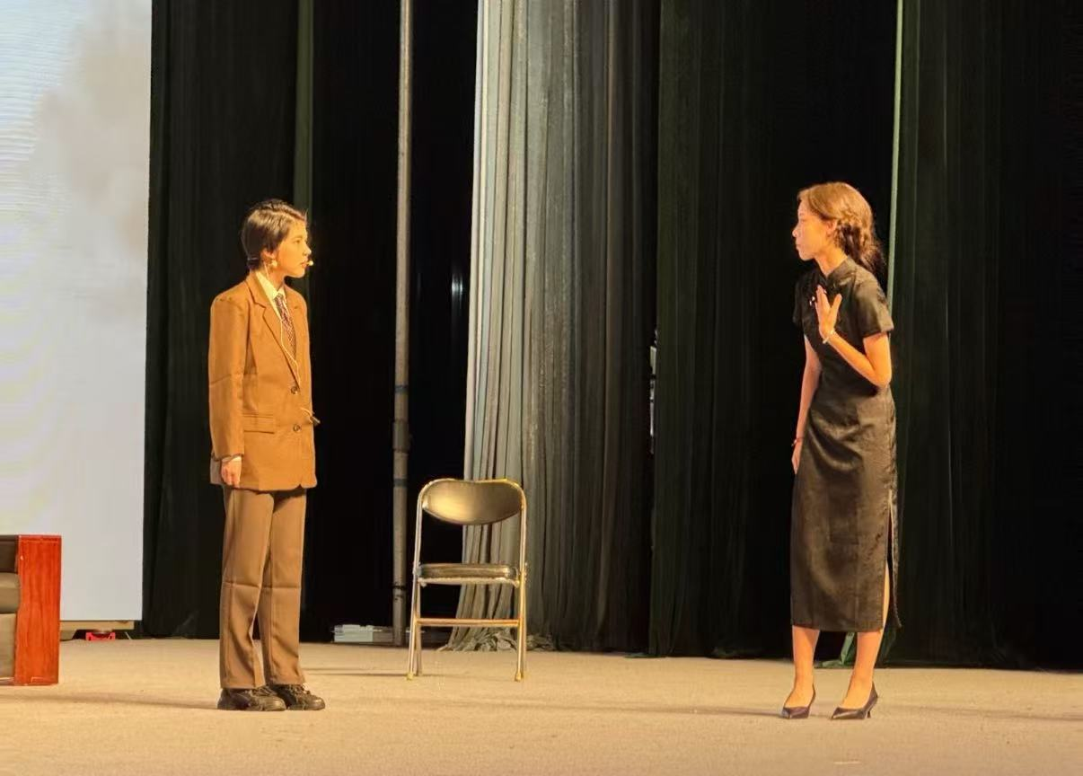 Two students performing a scene on stage at a school drama festival