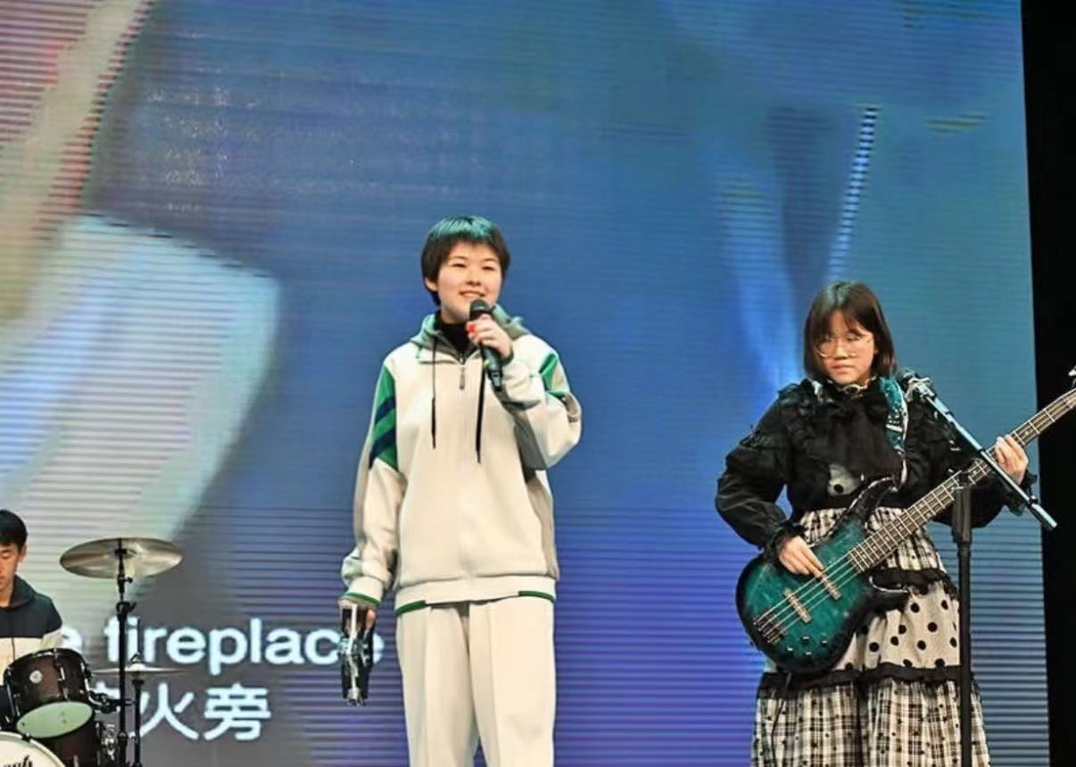 Student vocalist performing with a rock band at a school arts festival